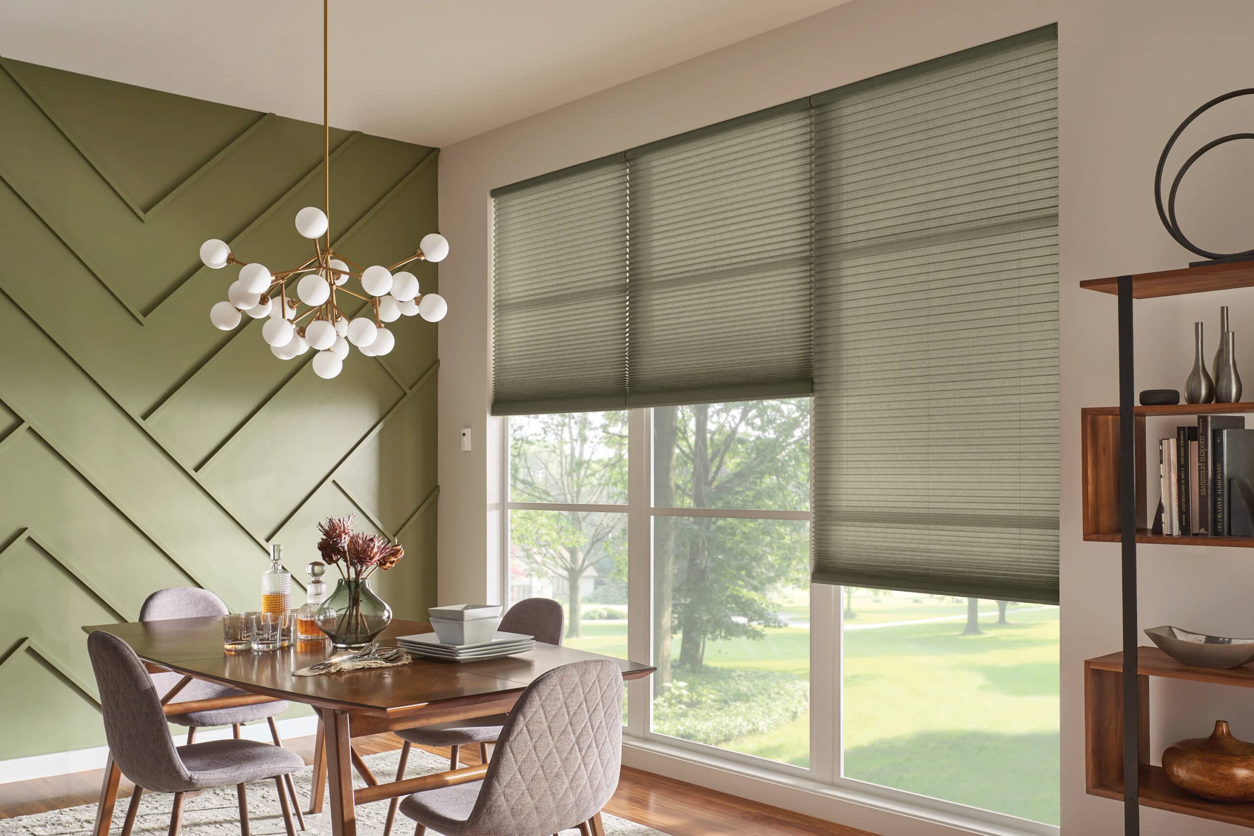 Green cellular shades hanging in a dining room filtering in natural light.