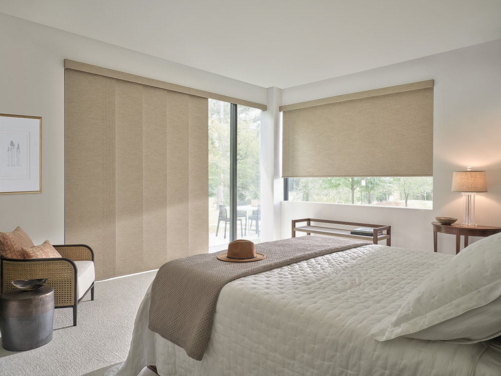 Roller shades letting in natural light into a master bedroom.